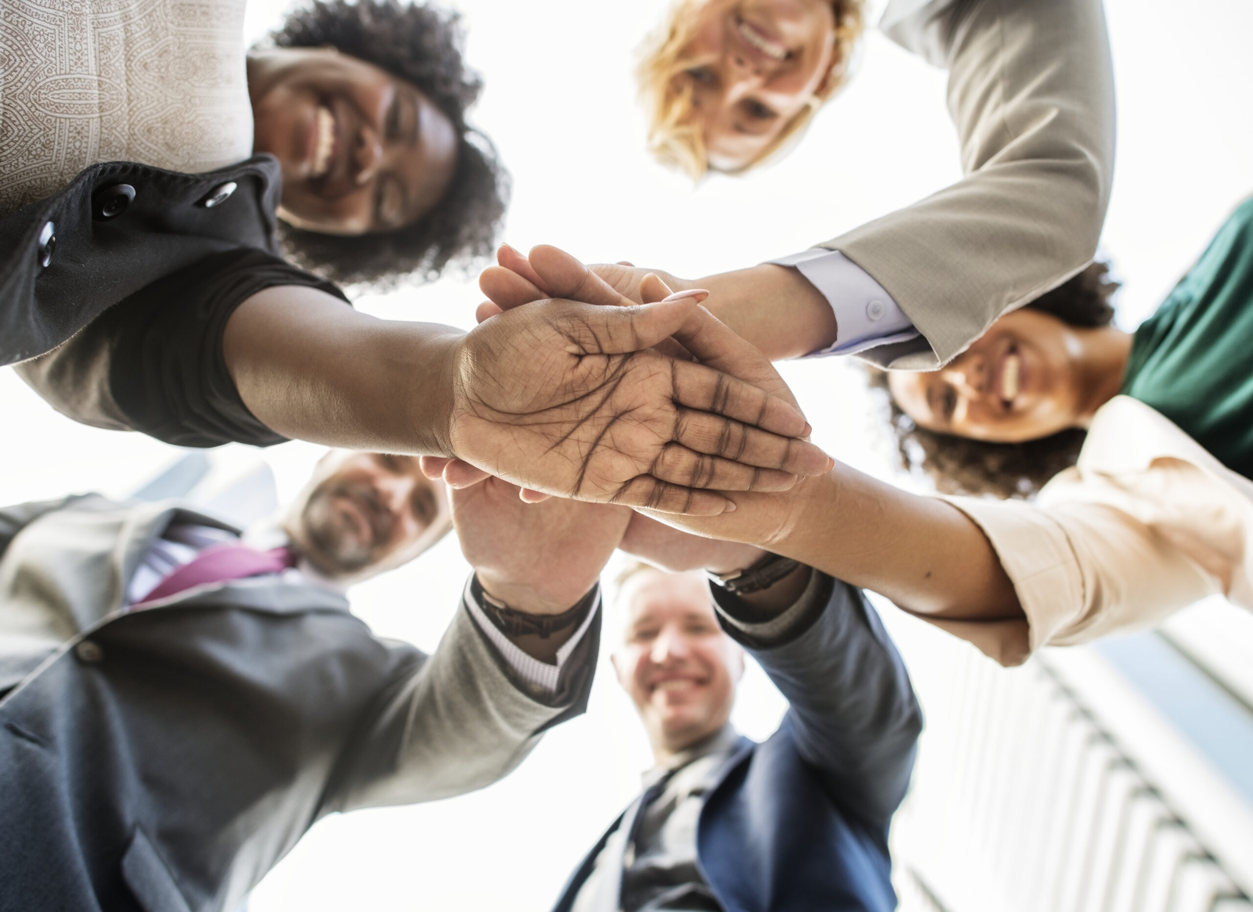 Diverse professionals stacking hands in unity, celebrating team success and shared goals.